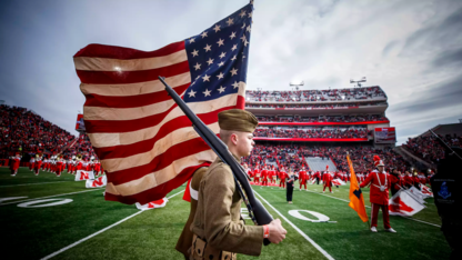 Members of the University of Nebraska–Lincoln ROTC color guard carry flags onto the field wearing authentic World War I uniforms as part of a Veterans Day observance in 2018. The Huskers will hold national anthem tryouts for the 2019-20 academic year on Aug. 14.