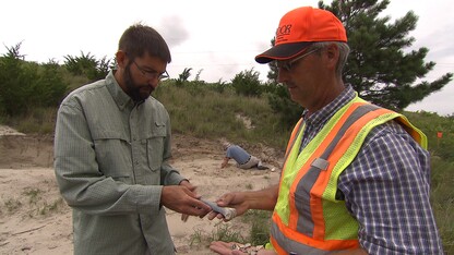 Two men hold a bone between them at a construction site.