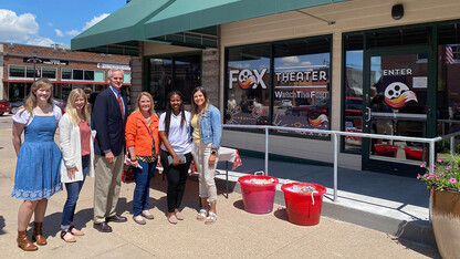 Student Fellows (from left) Alicia Pannell, Tori Pedersen, and Janet Kabetesi stand with Community Fellows Andrea McClintic and Stephanie Novoa in front of the Fox Theater Ribbon Cutting in Cozad, with Lt. Gov. Mike Foley.