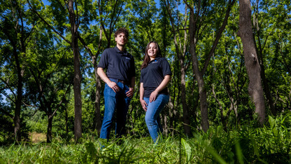 two environmental studies students posing in trees