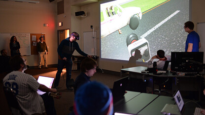 Ben Hartzell (left, in virtual reality goggles), a senior film and new media major, shows the progress of his team's final project in class on April 10.