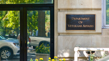 Vehicles are reflected in entrance doors to the Department of Veterans Affairs adjacent to Lafayette Park near the White House.