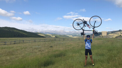 Nebraska's Chin Kiong Tee raises his bike for a photo in Wyoming's Bighorn National Forest. Tee's summer adventure featured a coast-to-coast bike ride in support of cancer victims.