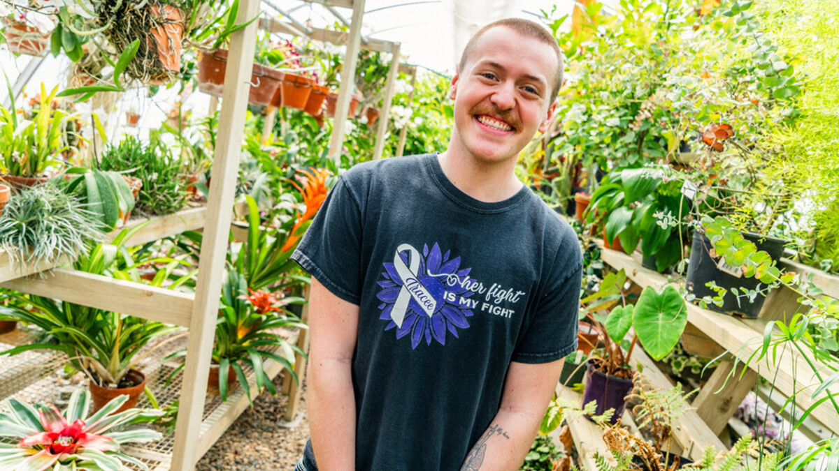 Trey Lamkins is photographed among potted plants.