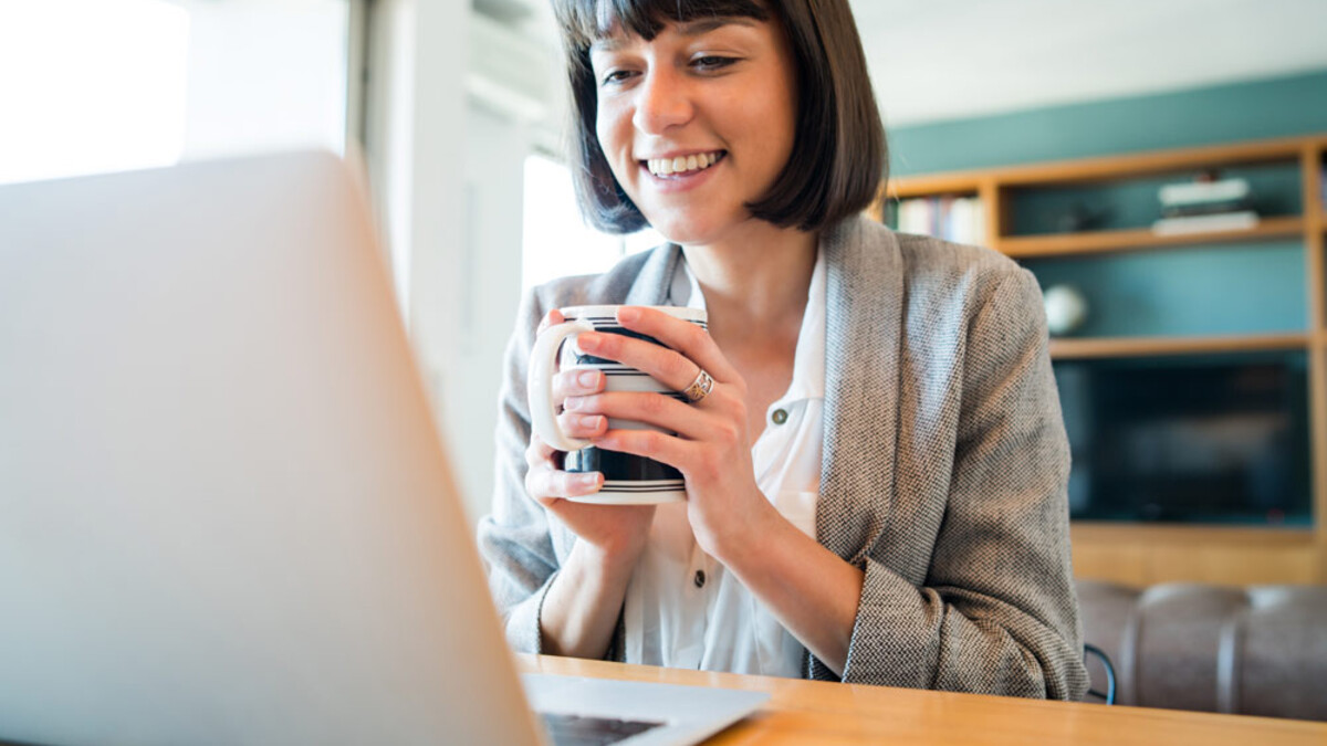 Women on laptop for virtual meeting holding coffee mug