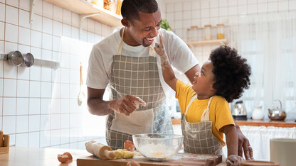 Dad and child baking together in a kitchen.