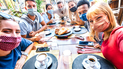 A group of friends meets up at a coffee house and takes a photo in masks.