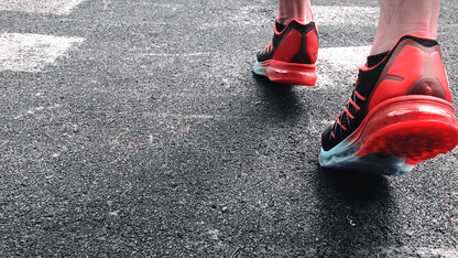 A person wearing red tennis shoes walking on concrete pavement