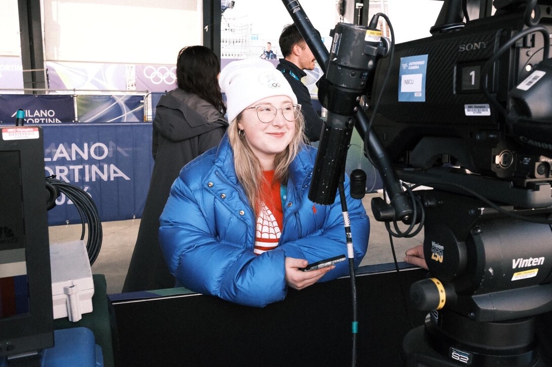 Frey next to NBCU broadcast video equipment in the media area for the Milano Cortina 2026 Winter Olympics.