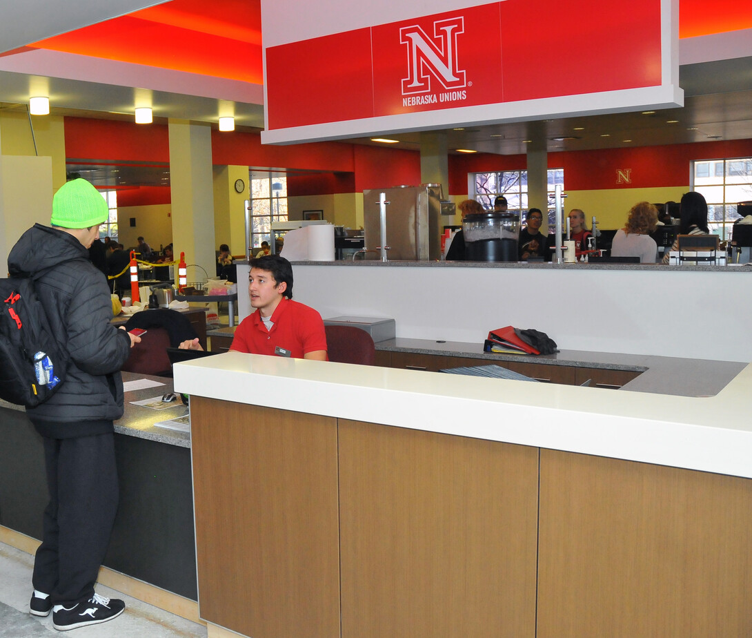 Micah Lindblad assists a student at the new welcome desk inside the Nebraska Union.