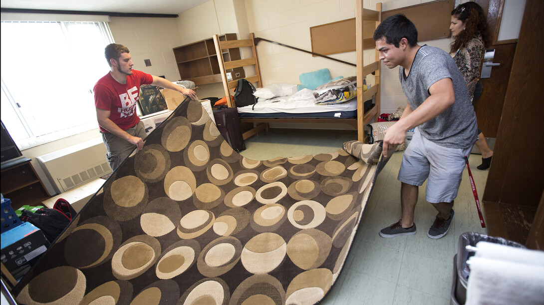 Michelle Huesca of Omaha (right) and Matt Willis of Blair unroll their carpet in their Smith Hall room.