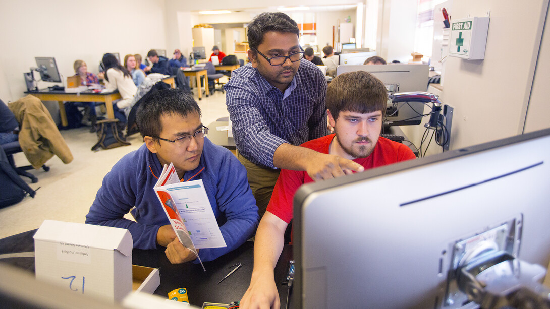 Nebraska researcher Santosh Pitla (center) assists students with a sensor-building project. Pitla is leading a new research project that will update techniques used to test tractors.