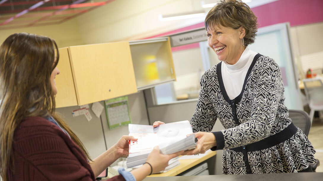 Teri Kaluza smiles as she hands a project off to a customer in the Pixel Lab. Kaluza has worked on campus for nearly 22 years.