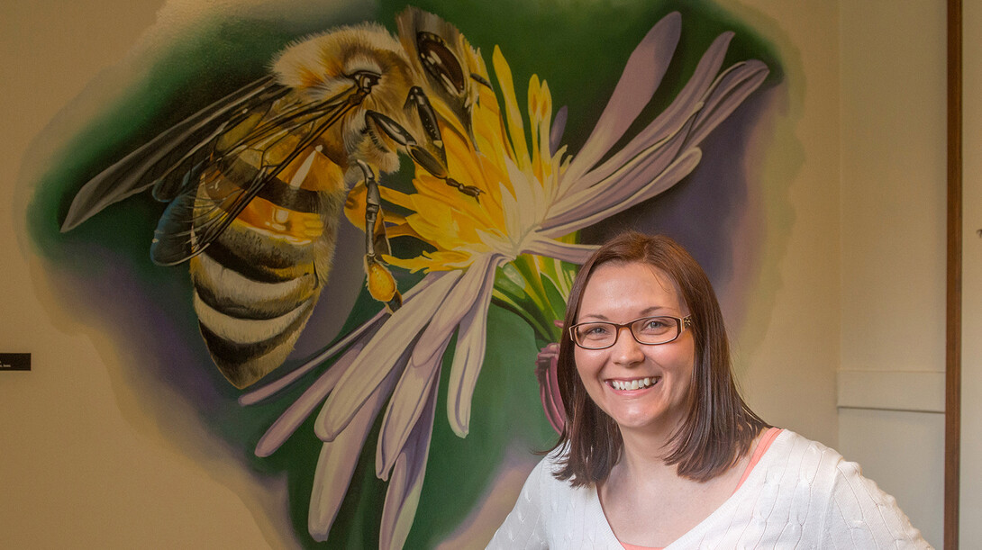 UNL researcher Erin Ingram stands in front of a bee mural in the hallways of Entomology Hall.