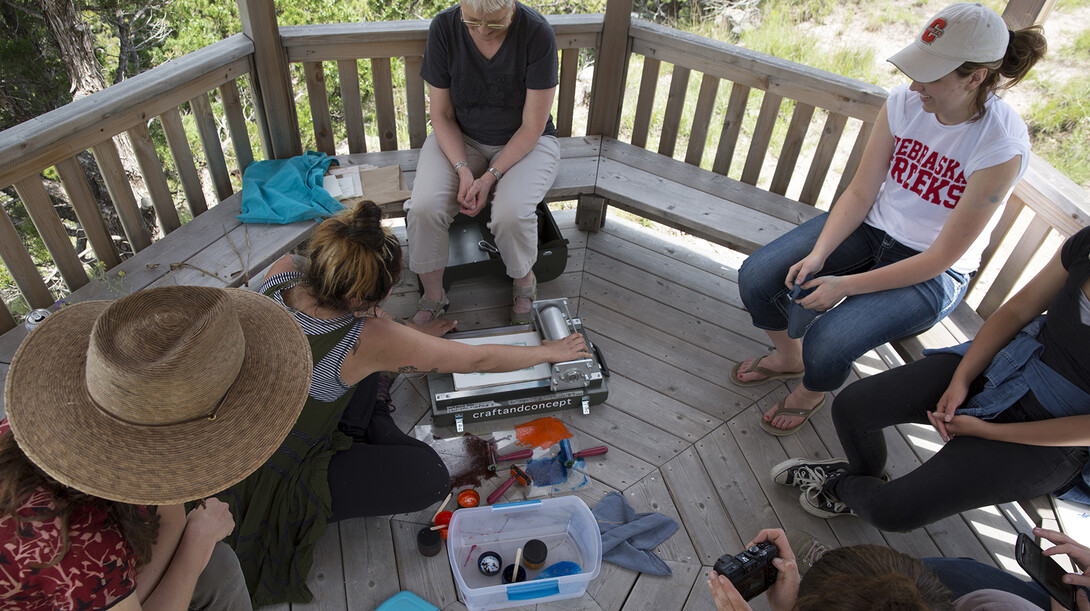 Students create prints of plant material in a gazebo atop a bluff at Cedar Point Biological Station. Kunc provided a backpack printing press that allowed students to generate designs while in the field.