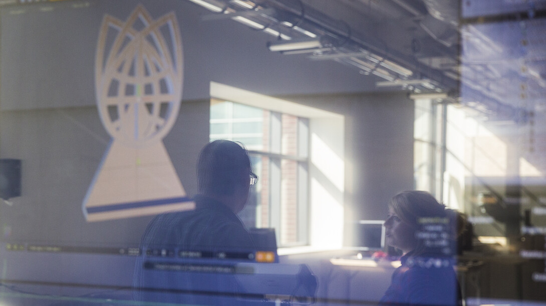 Reflected on a screen that shows the design of the Nebraska Innovation Campus ribbon cutting sculpture, Liana Owad (right) and Gregg Johnson discuss the project Oct. 6 in Nebraska Innovation Studio.