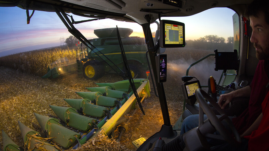 A farmer harvests corn while watching data regarding the harvest quality on a computer in his combine.
