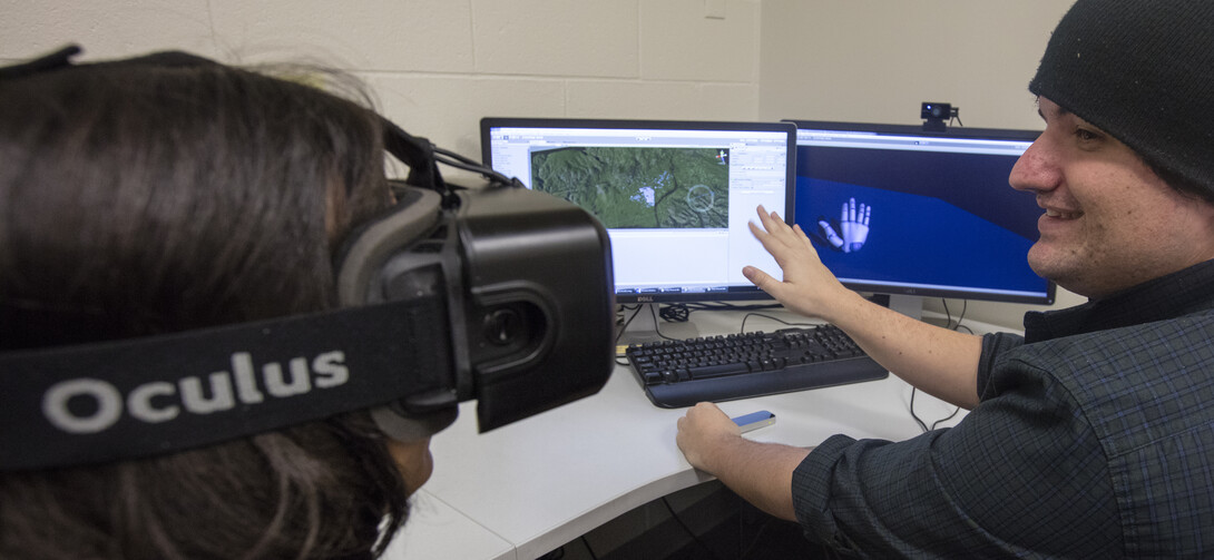 Zach Day demonstrates his work with visual reality headsets that will allow participants to tour ruins around the world. He is demonstrating an add on that allows the users hands to be part of the VR and manipulate objects in the program.