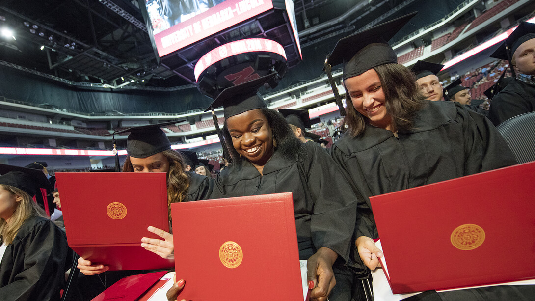 Nebraska grads examine their diplomas during a commencement exercise in Pinnacle Bank Arena. Graduates who have lost diplomas due to spring floods can get them replaced at no cost through a partnership between the Nebraska Alumni Association and University Registrar.