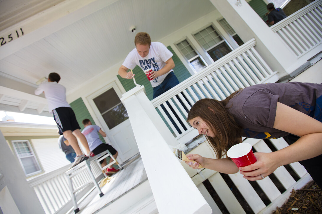 Kate Christensen from Utah works on a porch rail while her husband, L1 law student Theron Christensen works on the porch column at a house on B Street. Students, faculty and staff from the College of Law participated in the city-wide Paint-A-Thon by painting four houses. August 20, 2016.