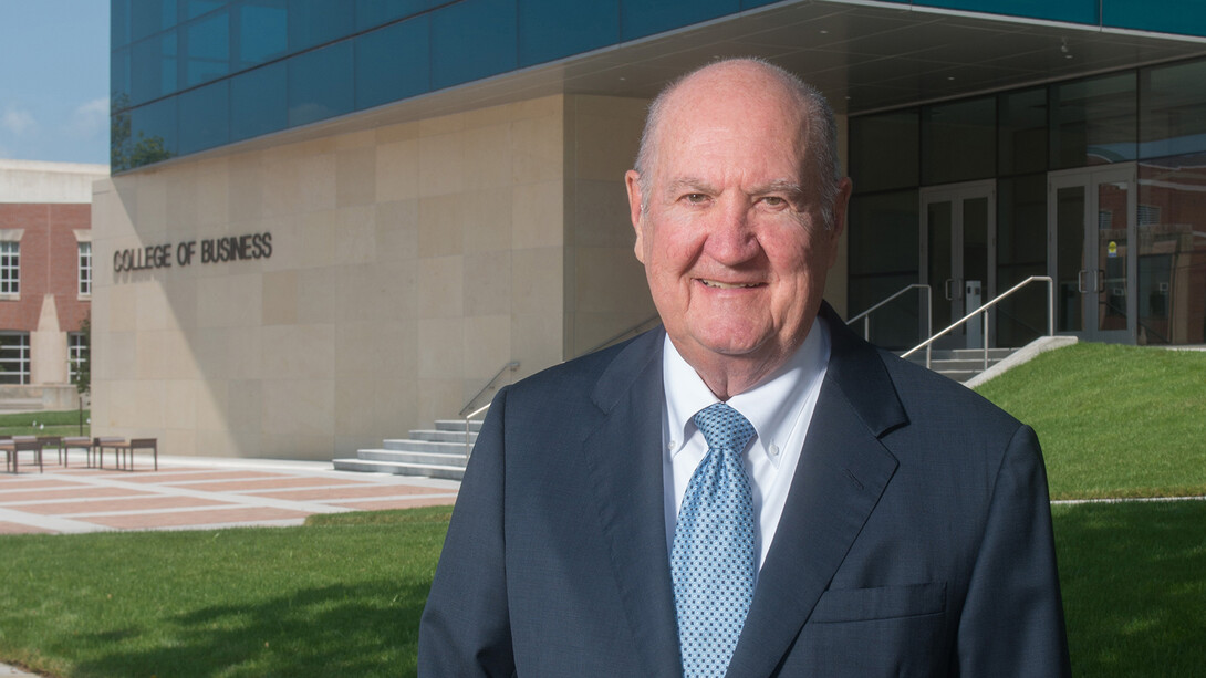 Howard L. Hawks standing in front of the College of Business, which was named in his honor.