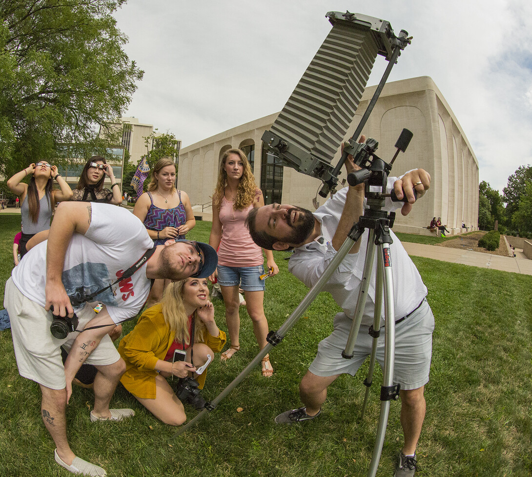 Walker Pickering (right) and introductory to photography students look at the eclipse through a view camera in the Sheldon Sculpture Garden.