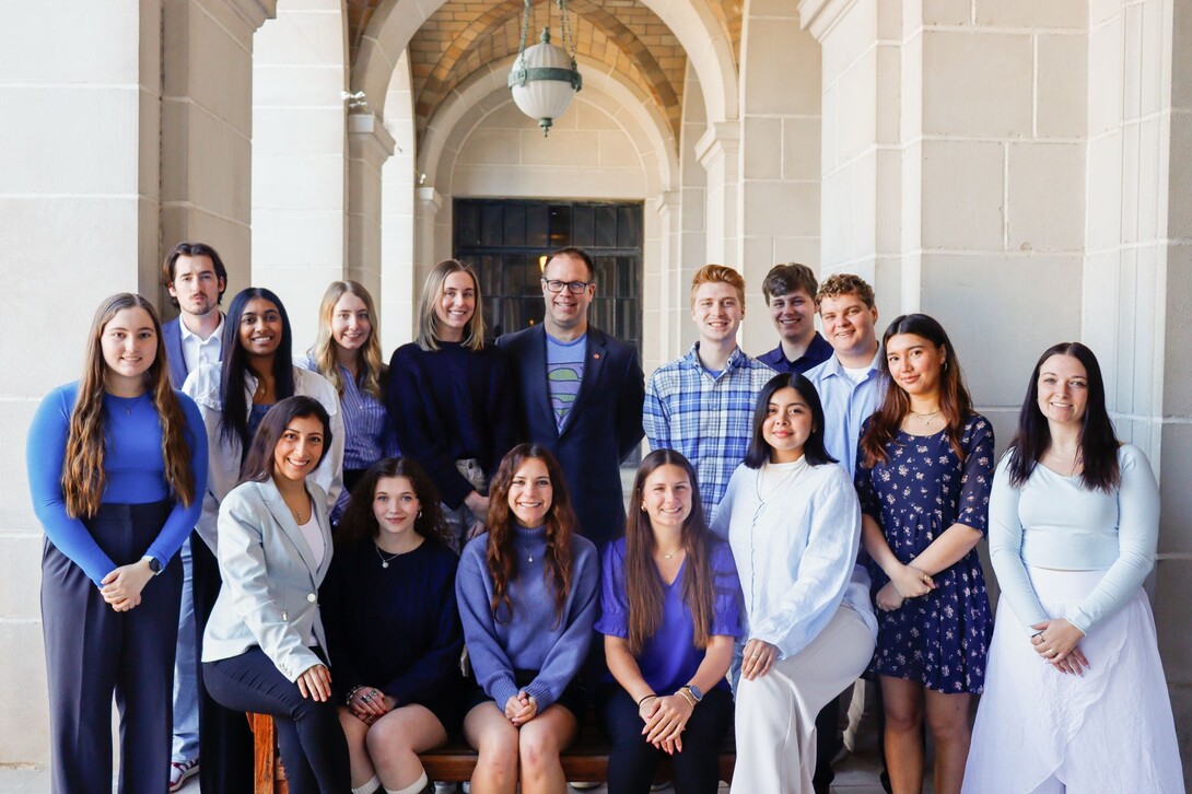 Students dressed in blue, black and white are gathered together for a photo.