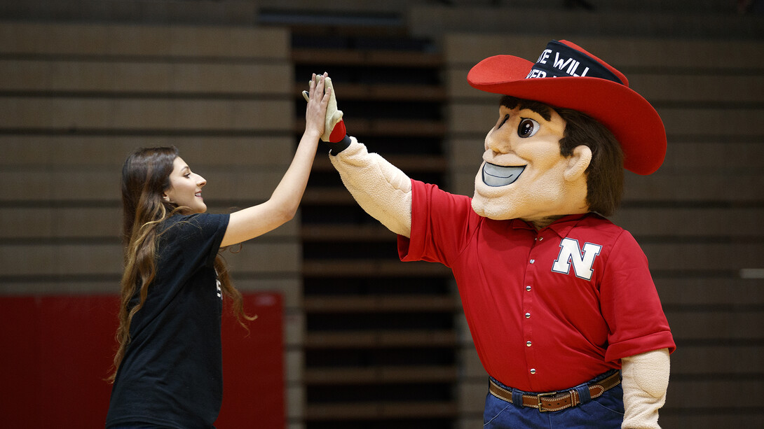 Ayat Aribi, external vice president of ASUN, gets a high five from Herbie Husker as she approaches the stage to talk during the Feb. 14 rally.