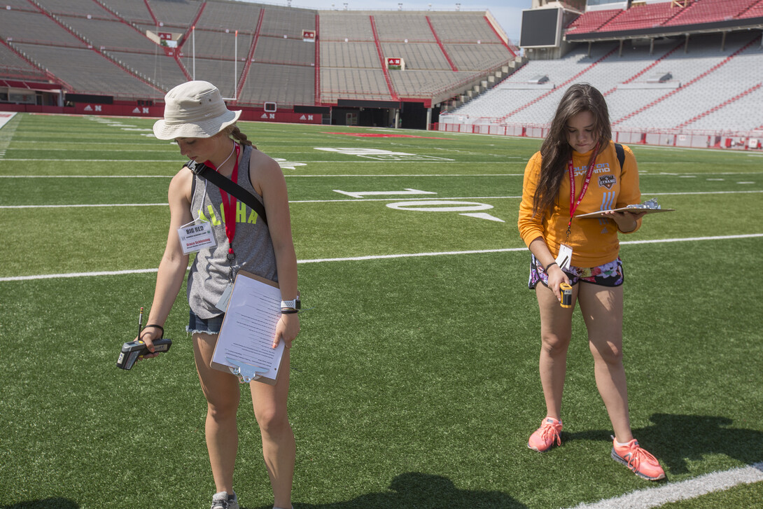 Weather campers Grace Schlepping (left) and Awinita Bunner take temperature measurements on the turf of Memorial Stadium June 14.