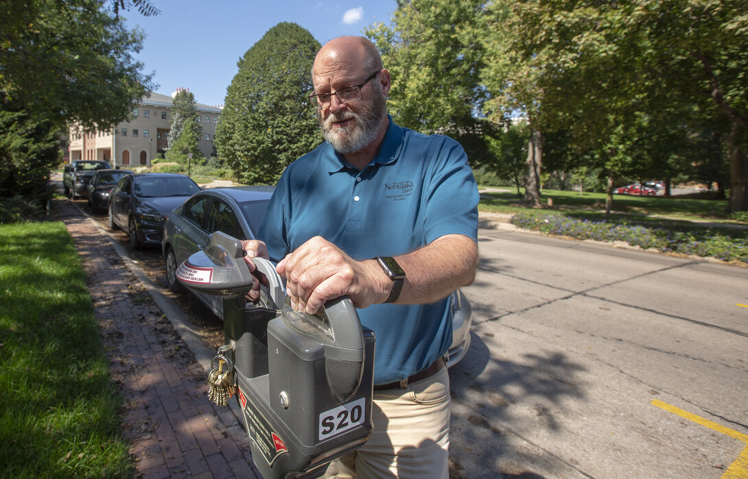 Bill Manning checks a malfunctioning parking meter on East Campus. Manning, who has worked for 40 years at the university, is among the 960 faculty and staff who will receive honors for years of service on Sept. 25.