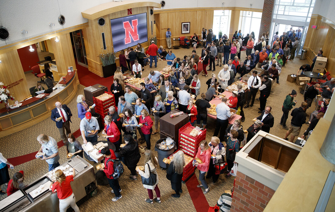 Faculty and staff line up in the Van Brunt Visitors Center to pick up a lunch during the universitywide picnic that followed the service celebration. Fall rains forced food pickup for the picnic indoors.