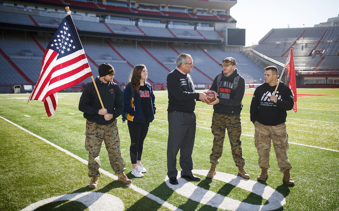 Bill Moos, Nebraska's director of athletics, hands the game ball off to ruck march volunteers in Memorial Stadium on Nov. 14.