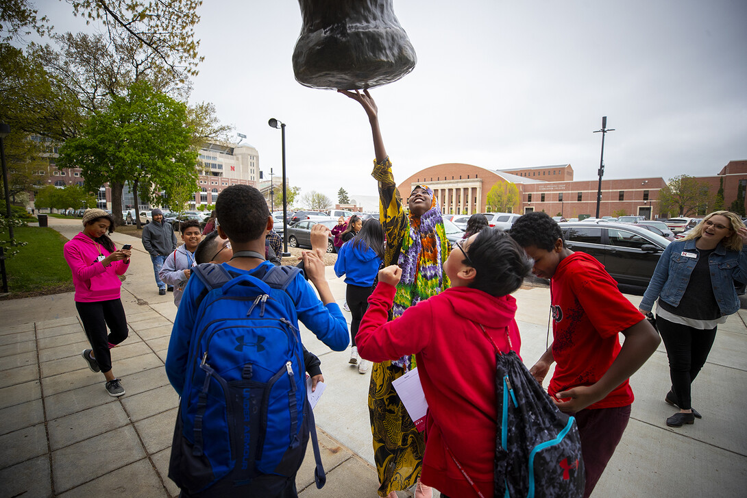 Lexington middle school students and chaperones reach to touch the good luck foot of the mammoth sculpture outside of Morrill Hall during a campus tour on May 1. Along with tours, Nebraska's middle school-related programs include Next Chapter at Nebraska, Big Red Stars and Middle School College Access Days.