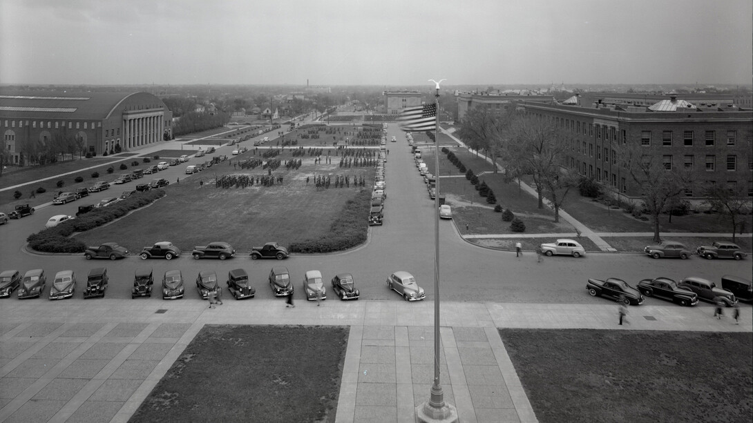 Nebraska ROTC students march on the green space east of Memorial Stadium in for a Chancellor's Review in April 1942. Taken from atop Memorial Stadium, this image includes the Coliseum (left), Bessey Hall (right, bottom) and Morrill Hall (right, top)