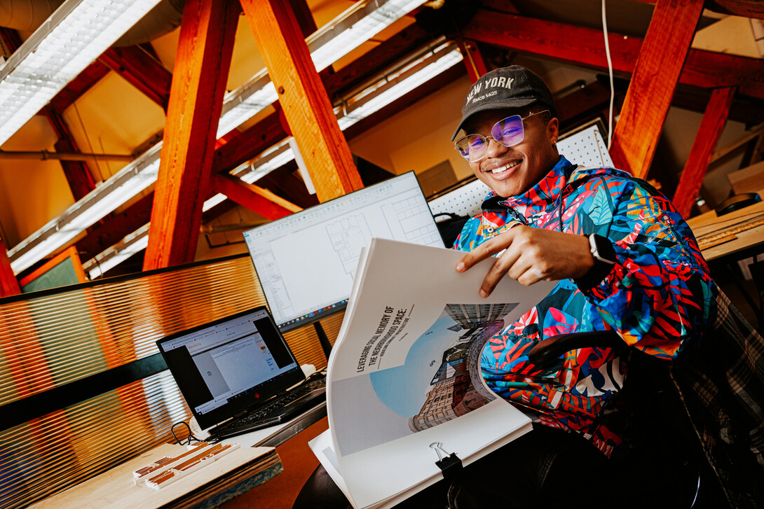 Jeremiah Brown smiles for a photo at a desk in Architecture Hall