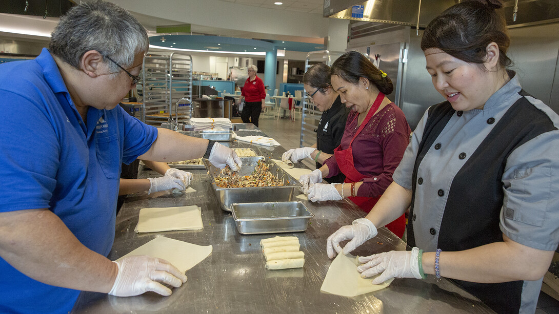 Team members work through the final pan of homemade egg roll filling in the World's Fare station in the Cather Dining Center. Pictured at the table (from left) is Tri Tu, Kim Nguyen (hidden by Tu), Amy Tran, Ha Vu and Thom "Emily" Tran.