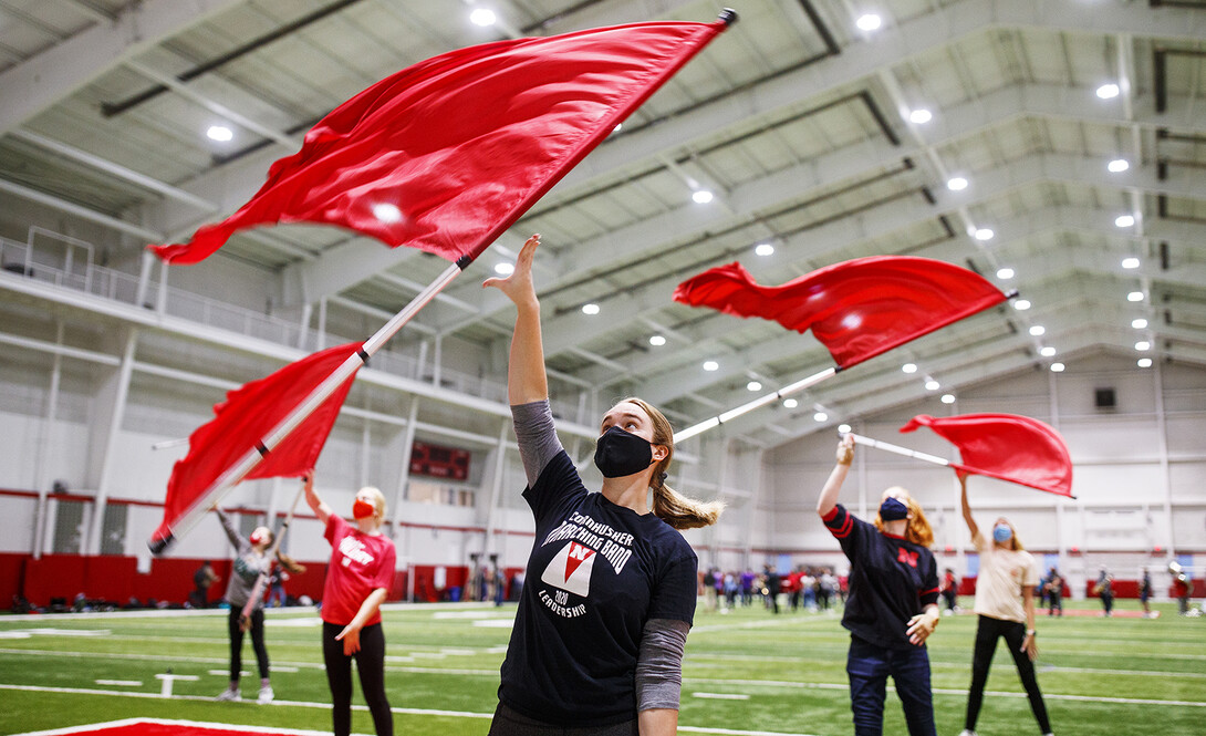 Michaela Smith and other members of the Cornhusker Marching Band color guard take their flags out for an early morning spit during practice in Cook Pavilion on Sept. 10.