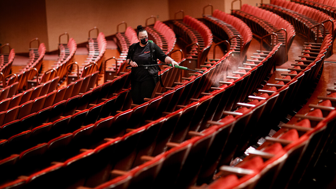 Jillian Stewart, assistant custodial services manager for the Lied Center for Performing Arts, disinfects seats after classes finished on Sept. 23. The Lied — which is among the first performing arts venues to reopen after national shutdowns in the spring — is using a multi-layered approach to protect against the spread of COVID-19. It is also hosting university classes in the day and performances in the evening.