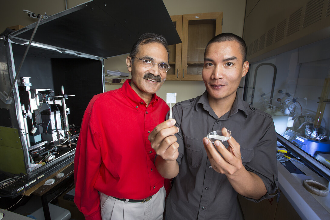 Ravi Saraf (left) and fellow researcher Chieu Van Nguyen, who is holding up a thin membrane on a slide cover.