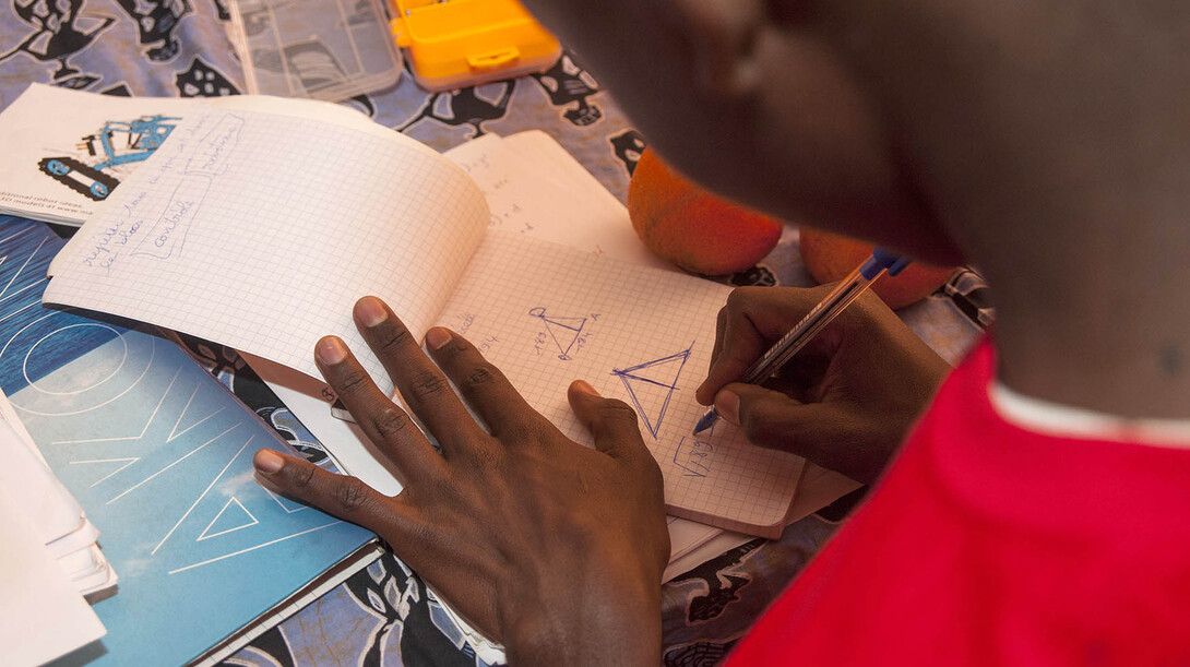 A student sketches possible changes to his teams robot during Sidy Ndao's robotics camp in Dakar, Sengal.
