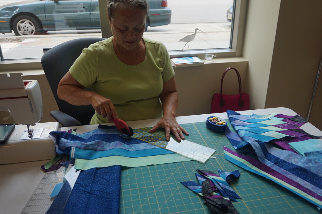 Artist Gwen Westerman cuts fabric during her first visit to the Great Plains Art Museum in early September. Westerman, the 2015 Elizabeth Rubendall Artist in Residence, will complete the artwork she started then during her next visit, Nov. 11-14.