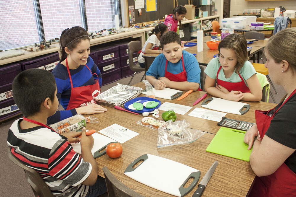 (From left) Giovanni Martinez, volunteer Denise McEnaney, Emmanuel Gallegos, Riah Zwicki and volunteer Julie Hegemann work on an exercise during the WeCook program Feb. 18 at West Lincoln Elementary.