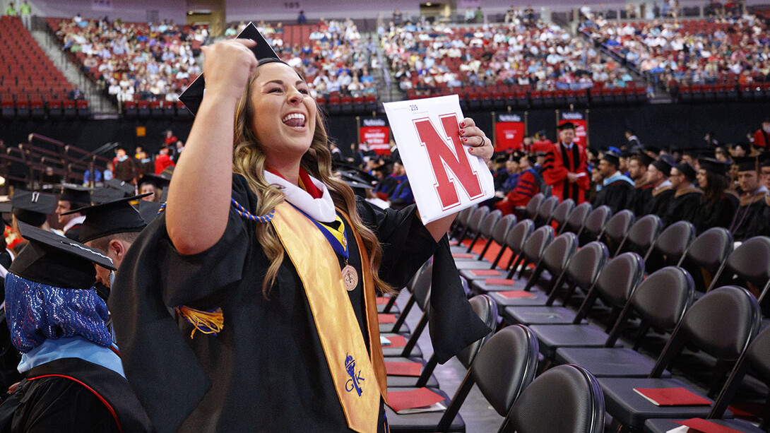 Alexandria Leavenworth gestures to her family and friends after receiving her master's degree in journalism and mass communications Friday at Pinnacle Bank Arena.