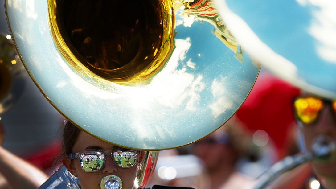 Band members are reflected in Kelsey Reeves' mirrored sunglasses as she plays her sousaphone during Cornhusker Marching Band practice Aug. 16 in Memorial Stadium.