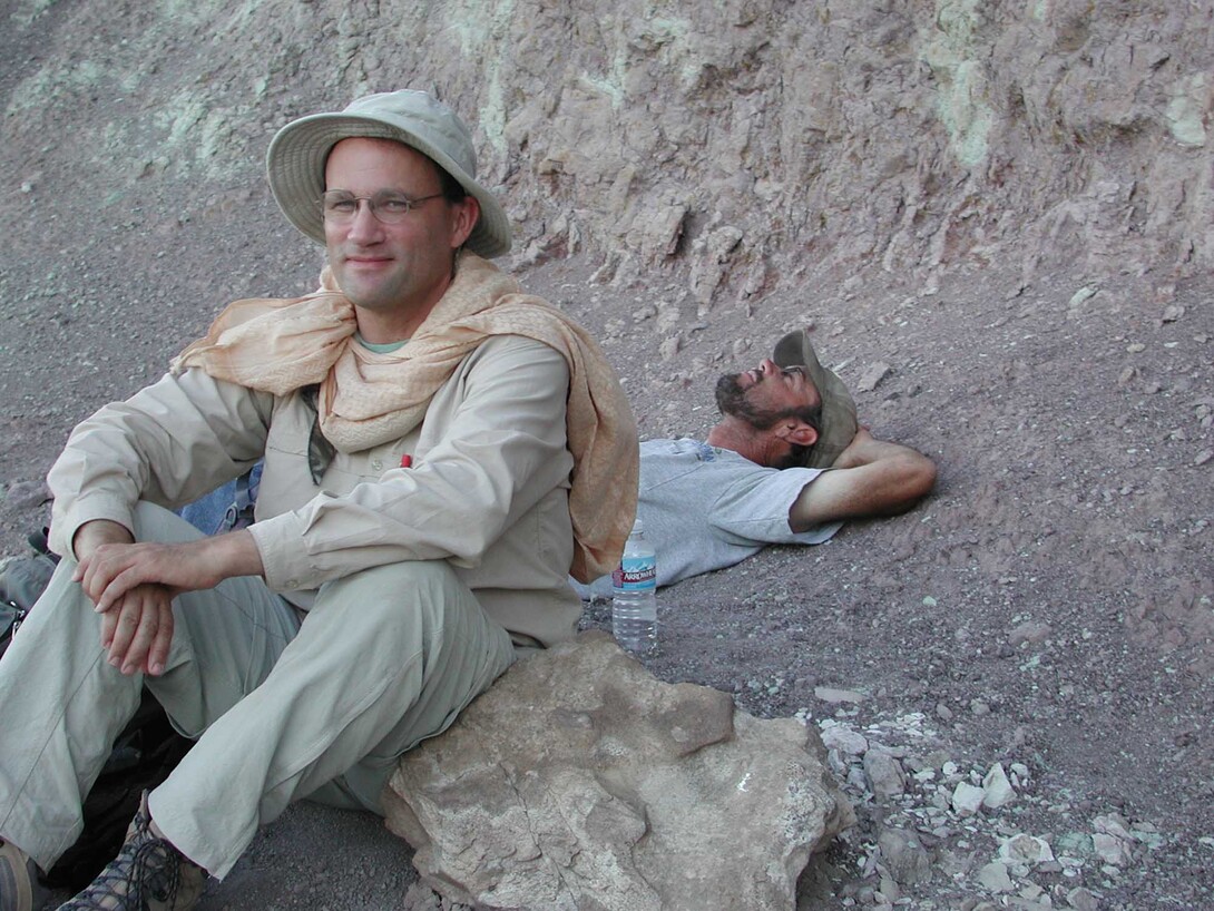 Matt Joeckel (front) and colleague, Gary Hunt, rest at the base of a Utah cliff face.