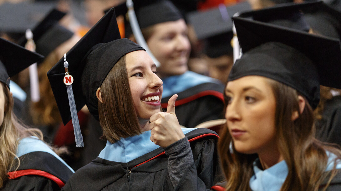 Rebecca Carr gives a thumbs-up to family and friends at the beginning of the graduate and professional degrees ceremony Dec. 15 at Pinnacle Bank Arena. Carr earned a Master of Arts.