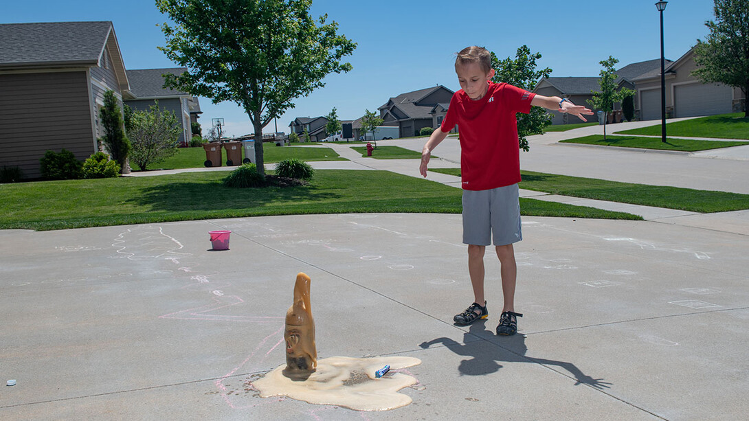 Evan Washburn watches the reaction after dropping a Mentos candy into a soda bottle in his family’s driveway. The activity was part of the Virtual Vibes 4-H camp.