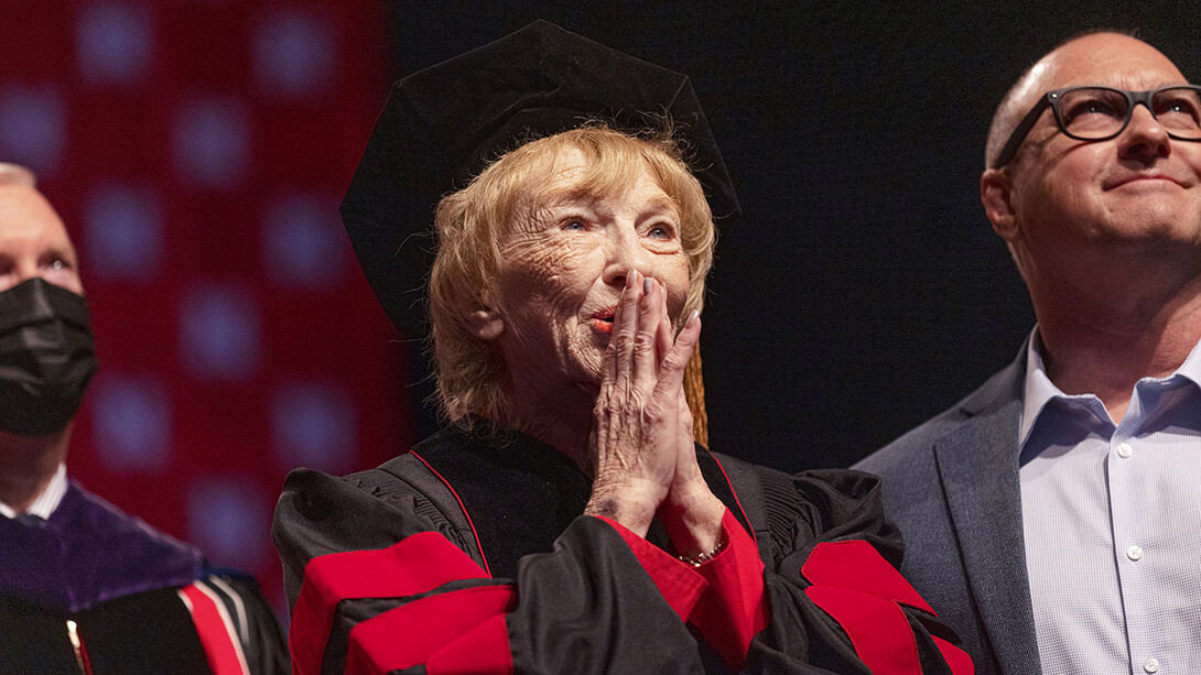 Leta Powell Drake, local television pioneer and Husker alumna, watches a video about her career on the scoreboard during the undergraduate commencement ceremony Aug. 14 at Pinnacle Bank Arena. The university presented Drake with an honorary Doctor of Humane Letters during the ceremony. Her son, Aaron (right), watches with her.