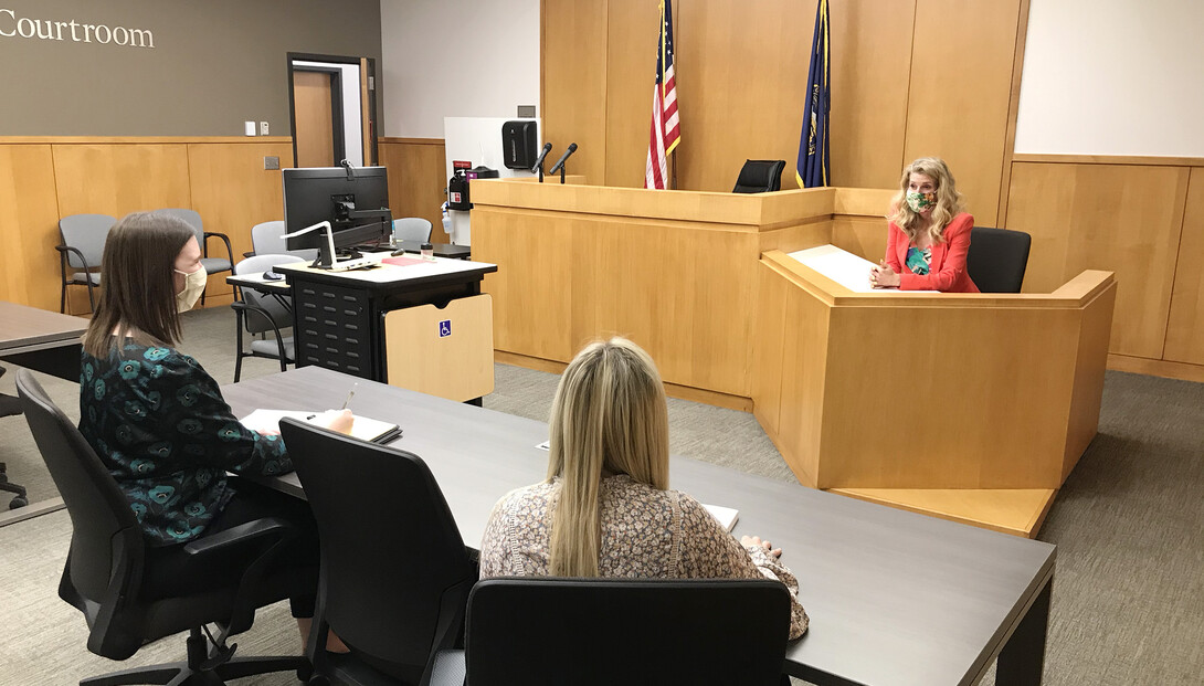 Michelle Paxton, director of the Children's Justice Clinic, talks with two student attorneys in the Judge Donald R. and Janice C. Ross Courtroom in the College of Law. Clinic student attorneys practice with Paxton before going to court.