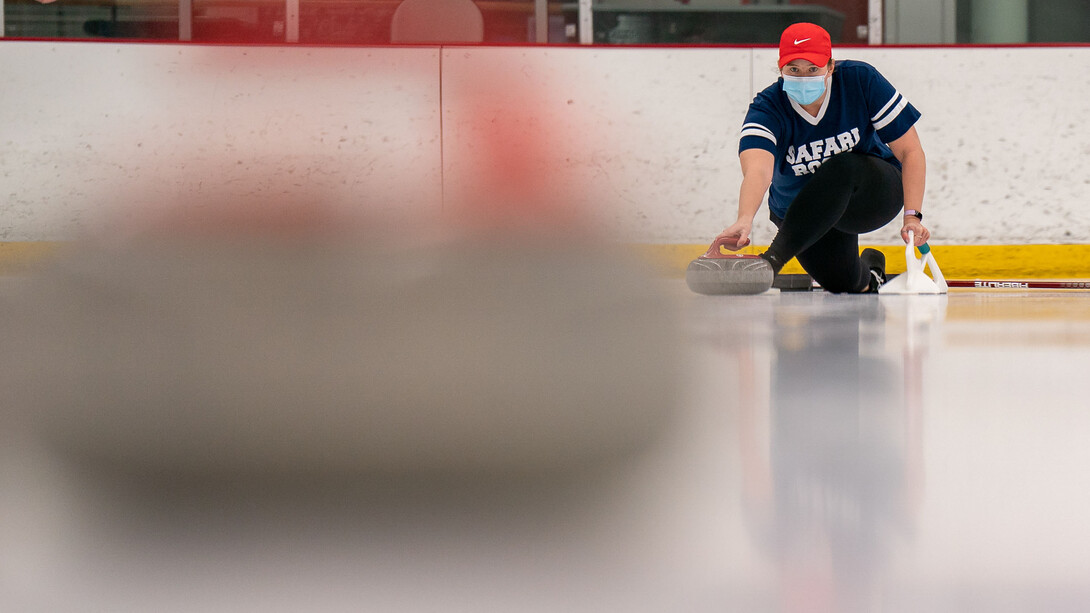 A curler throws the curling stone down the ice lane.
